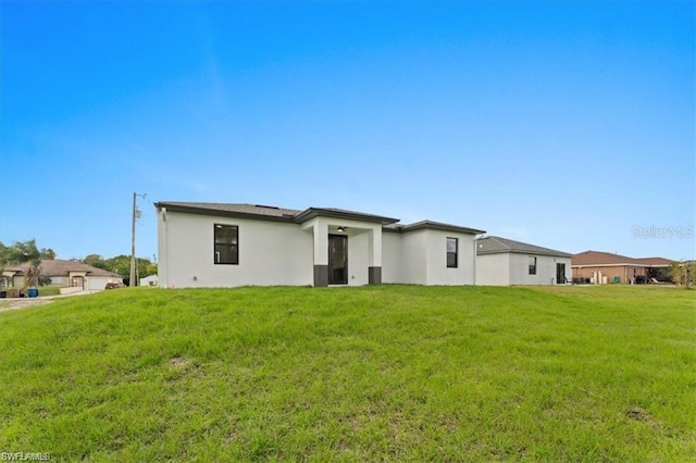731 Colyer St E, Lehigh Acres, FL 33974 - rear view of house with stucco siding and a yard