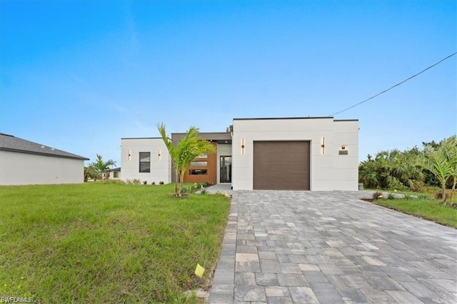 731 Colyer St E, Lehigh Acres, FL 33974 - contemporary house featuring a garage, a front lawn, decorative driveway, and stucco siding