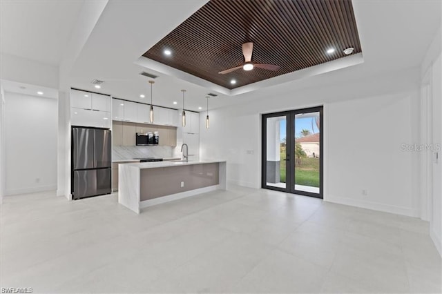 731 Colyer St E, Lehigh Acres, FL 33974 - kitchen with stainless steel appliances, modern cabinets, a tray ceiling, white cabinets, and light countertops