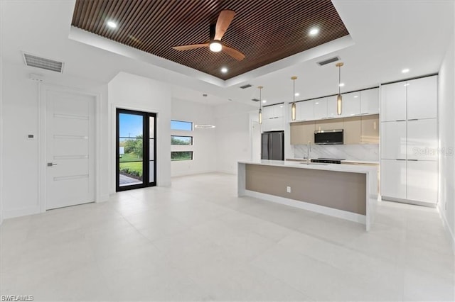 731 Colyer St E, Lehigh Acres, FL 33974 - kitchen featuring a tray ceiling, stainless steel microwave, freestanding refrigerator, modern cabinets, and white cabinets