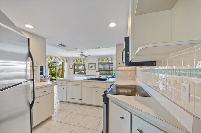 kitchen with appliances with stainless steel finishes, a sink, light countertops, light tile patterned floors, and a peninsula
