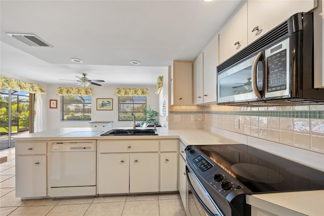 kitchen with white dishwasher, stainless steel microwave, black / electric stove, a sink, and a peninsula