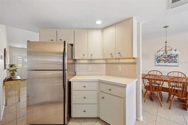 kitchen with freestanding refrigerator, cream cabinets, light countertops, light tile patterned floors, and recessed lighting