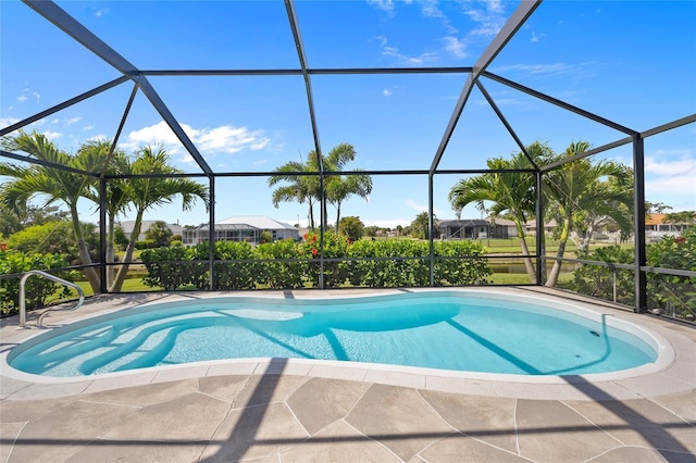 outdoor pool featuring glass enclosure and a patio