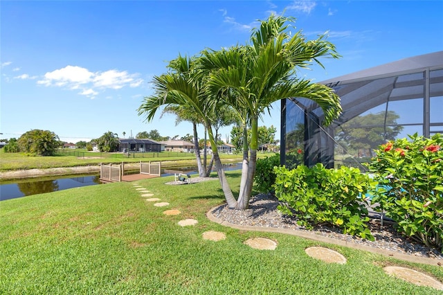 view of green lawn featuring a water view and a lanai