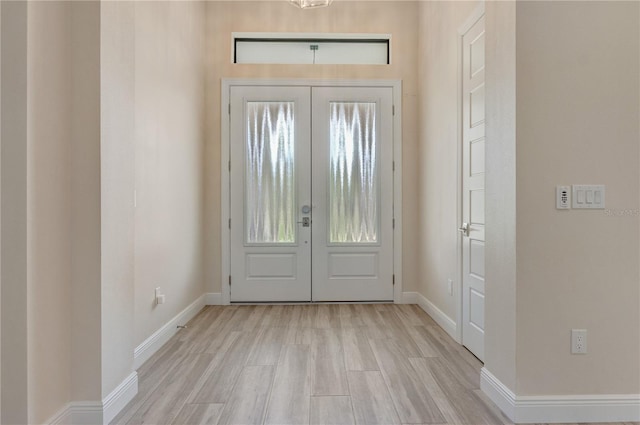entrance foyer featuring french doors, light wood-style floors, and baseboards
