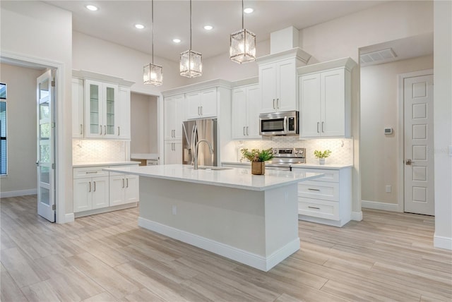 kitchen with appliances with stainless steel finishes, a sink, light countertops, white cabinetry, and recessed lighting