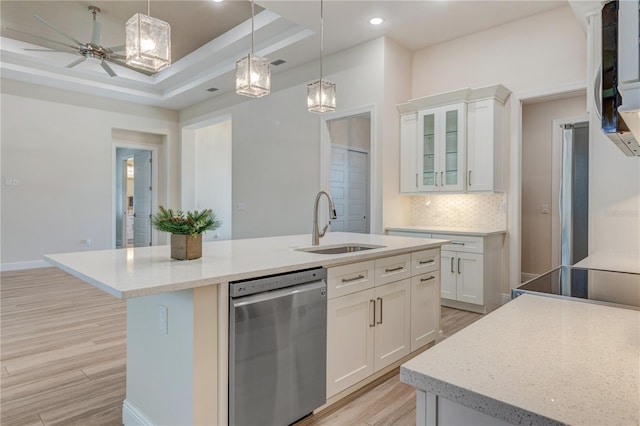 kitchen with stainless steel dishwasher, light wood-style flooring, a sink, decorative backsplash, and a kitchen island with sink