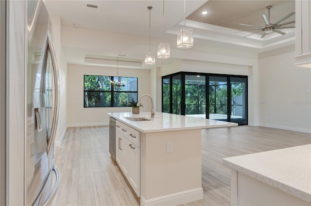 kitchen featuring appliances with stainless steel finishes, a tray ceiling, a sink, a chandelier, and recessed lighting