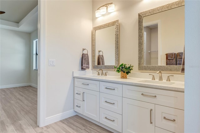 bathroom with wood finished floors, double vanity, and baseboards
