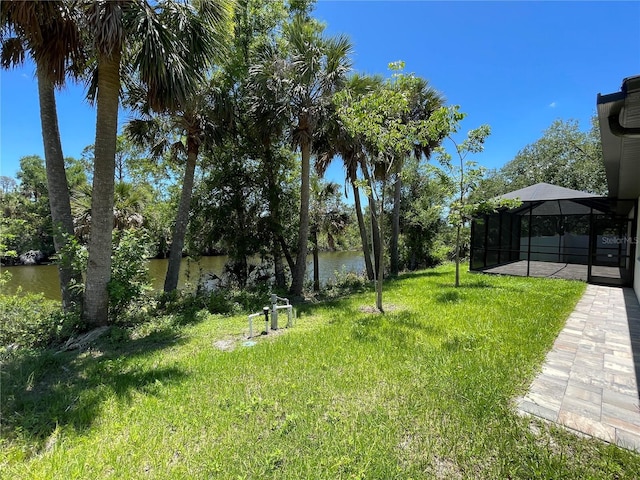 view of grassy yard with a water view and a lanai
