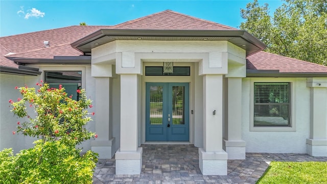 doorway to property with a shingled roof, stucco siding, and french doors