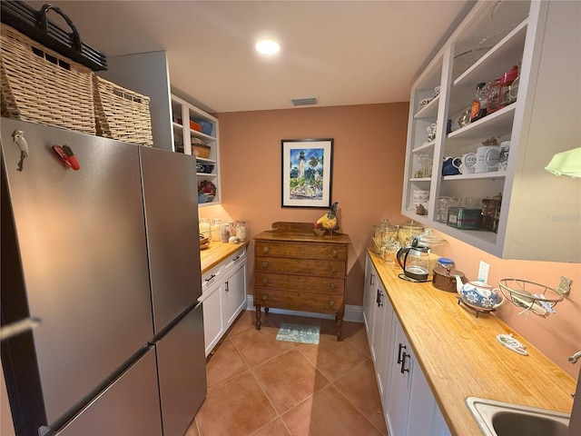 1005 S Sands Paradise Pt, Inverness, FL 34450 - kitchen with butcher block countertops, open shelves, freestanding refrigerator, light tile patterned floors, and a sink