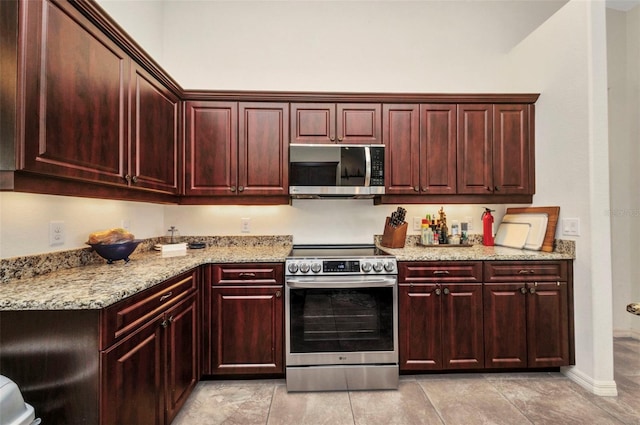 kitchen featuring appliances with stainless steel finishes, dark brown cabinets, light stone counters, and light tile patterned flooring