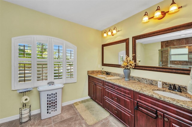 bathroom featuring plenty of natural light, a stall shower, baseboards, and double vanity