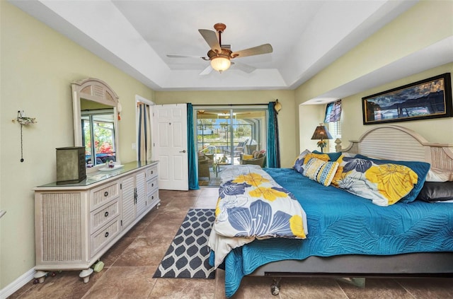 bedroom featuring multiple windows, a raised ceiling, access to exterior, and a ceiling fan