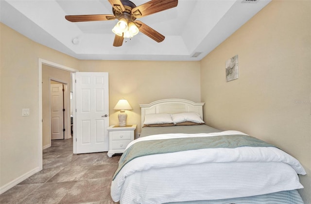 bedroom featuring a tray ceiling, baseboards, and ceiling fan