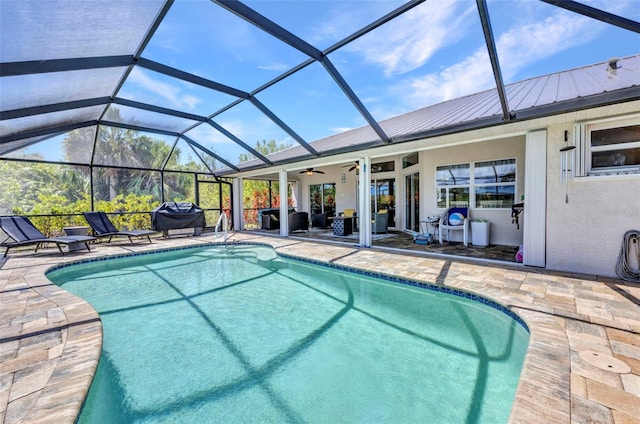 swimming pool with a patio area, grilling area, ceiling fan, and a lanai