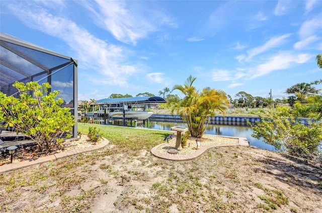 view of grassy yard with a water view, glass enclosure, a dock, and boat lift