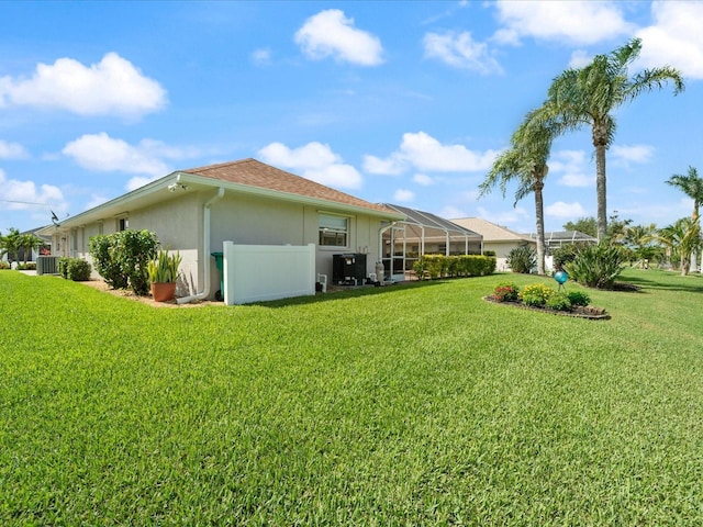 85 Long Meadow Ct, Rotonda West, FL 33947 - rear view of house with stucco siding, a lawn, a lanai, and central air condition unit