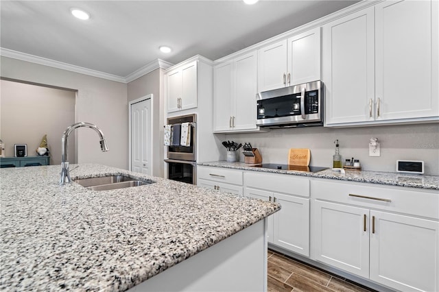 25308 Rupert Rd, Punta Gorda, FL 33983 - kitchen with stainless steel appliances, a sink, ornamental molding, white cabinets, and wood finished floors