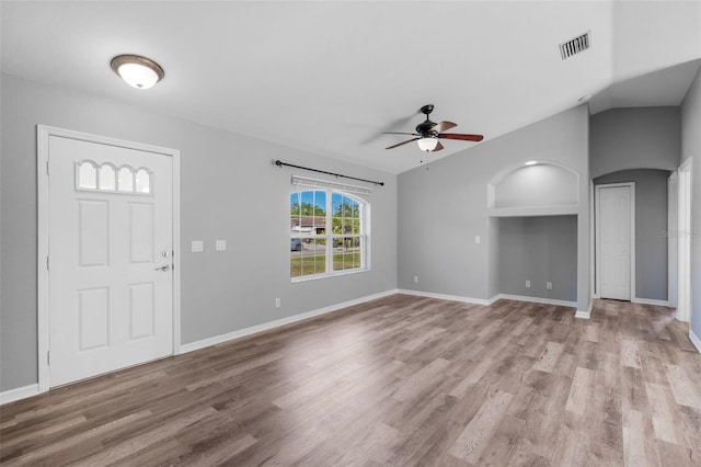 entryway featuring ceiling fan, wood finished floors, baseboards, arched walkways, and lofted ceiling