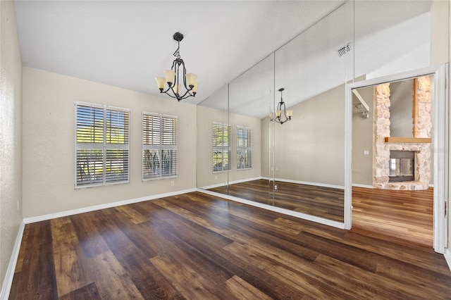 501 Fairmont Ter, Port Charlotte, FL 33954 - unfurnished dining area featuring a chandelier, vaulted ceiling, baseboards, wood finished floors, and a stone fireplace