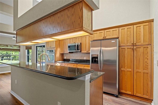 501 Fairmont Ter, Port Charlotte, FL 33954 - kitchen featuring appliances with stainless steel finishes, light wood-style flooring, decorative backsplash, an island with sink, and a sink