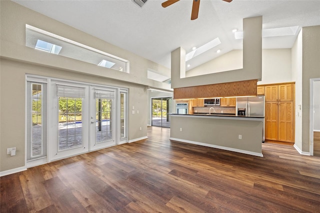 501 Fairmont Ter, Port Charlotte, FL 33954 - unfurnished living room with high vaulted ceiling, dark wood-style floors, ceiling fan, baseboards, and a skylight