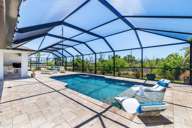 swimming pool with exterior kitchen, a patio area, and glass enclosure