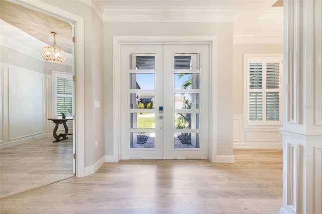 doorway featuring french doors, crown molding, light wood-style floors, and a chandelier