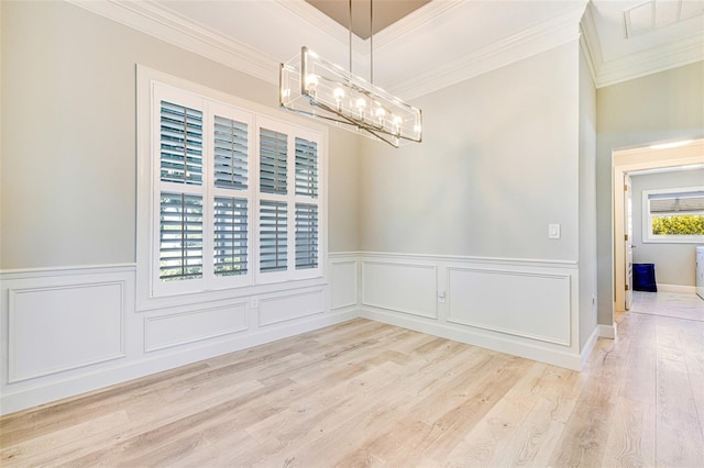 unfurnished dining area with ornamental molding, a chandelier, wood finished floors, and a wainscoted wall