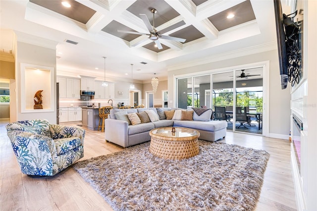 living area featuring a ceiling fan, ornamental molding, beamed ceiling, light wood-style floors, and a fireplace