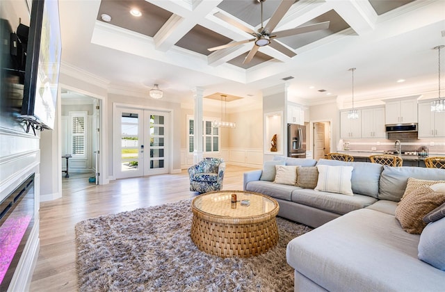 living room featuring crown molding, ceiling fan, beamed ceiling, coffered ceiling, and light wood-style flooring
