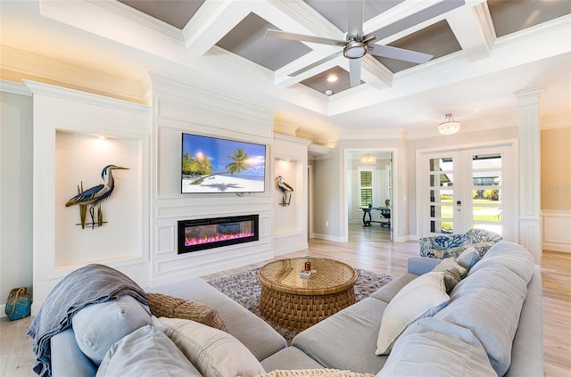 living area with crown molding, coffered ceiling, french doors, a glass covered fireplace, and a ceiling fan