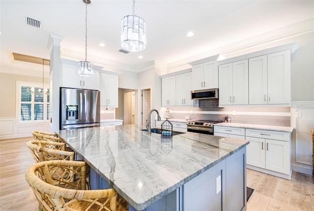 kitchen featuring appliances with stainless steel finishes, a sink, crown molding, a breakfast bar, and a spacious island