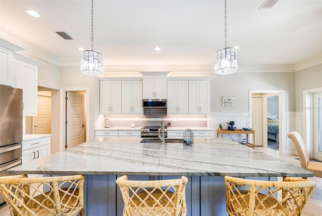 kitchen with a chandelier, stainless steel appliances, a breakfast bar area, a sink, and ornamental molding