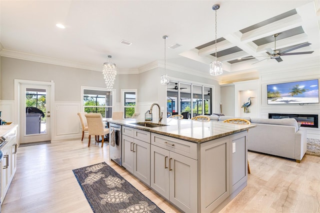 kitchen with a sink, ceiling fan, a decorative wall, stainless steel dishwasher, and crown molding