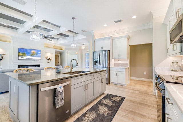kitchen featuring stainless steel appliances, a sink, open floor plan, crown molding, and a chandelier