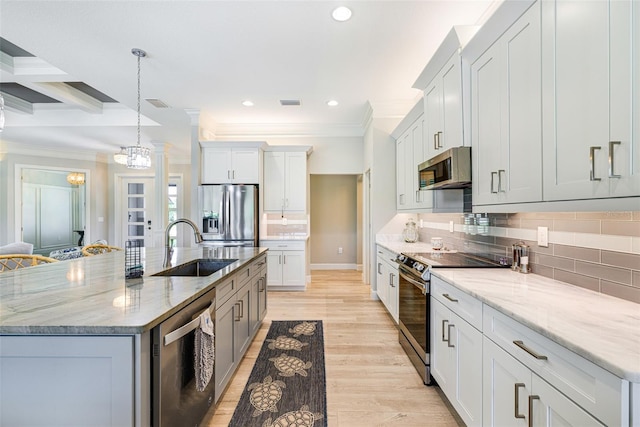 kitchen with appliances with stainless steel finishes, a sink, ornamental molding, recessed lighting, and an island with sink
