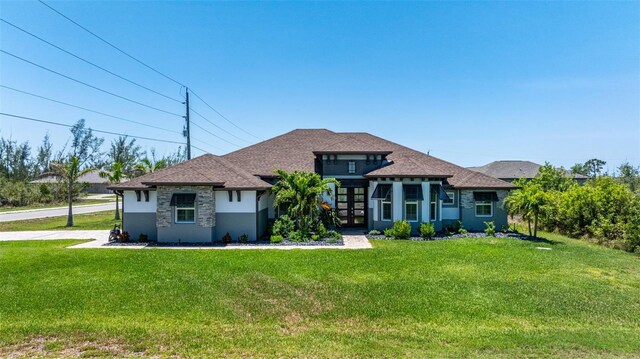 view of front of property featuring a front yard, stucco siding, french doors, and roof with shingles