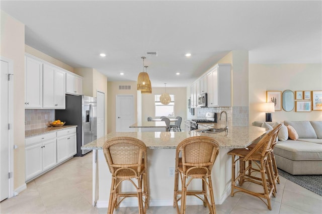 17629 Palmetto Pass Ln, Punta Gorda, FL 33982 - kitchen with appliances with stainless steel finishes, a sink, a peninsula, light stone countertops, and tasteful backsplash