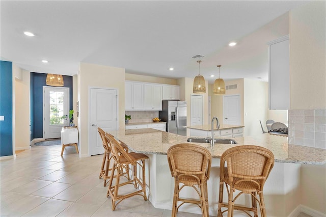 17629 Palmetto Pass Ln, Punta Gorda, FL 33982 - kitchen with stainless steel refrigerator with ice dispenser, a sink, a peninsula, decorative backsplash, and white cabinetry