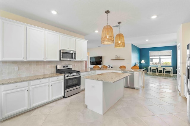 17629 Palmetto Pass Ln, Punta Gorda, FL 33982 - kitchen featuring stainless steel appliances, a peninsula, tasteful backsplash, white cabinetry, and a center island