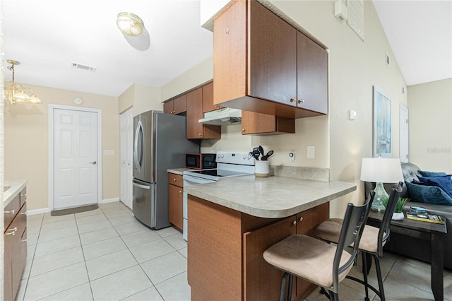 kitchen featuring electric stove, under cabinet range hood, freestanding refrigerator, a peninsula, and a breakfast bar area