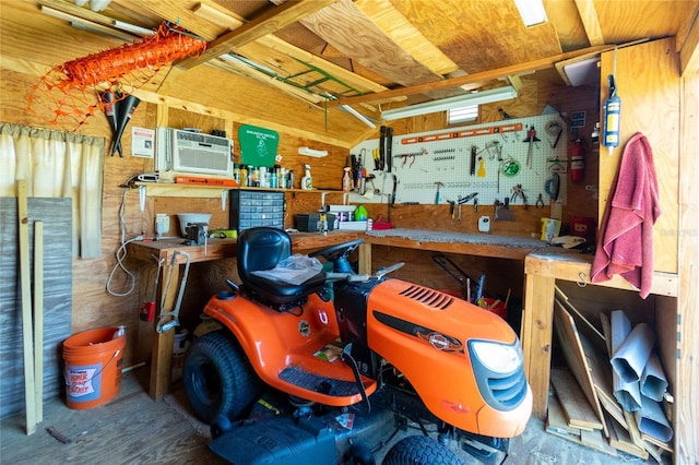 garage featuring a workshop area, wooden walls, and a wall unit AC