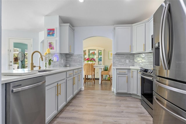 17396 Cox Ave, Port Charlotte, FL 33948 - kitchen featuring appliances with stainless steel finishes, a sink, arched walkways, light countertops, and tasteful backsplash