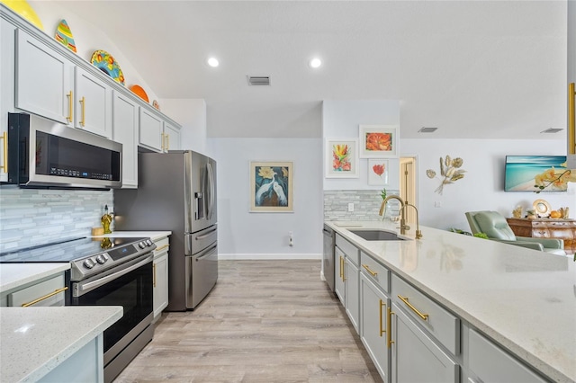 17396 Cox Ave, Port Charlotte, FL 33948 - kitchen with stainless steel appliances, a sink, tasteful backsplash, light wood-style floors, and light stone counters