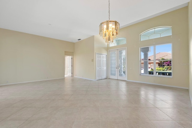 13783 Palmetto Point Ct, Port Charlotte, FL 33953 - unfurnished room featuring a chandelier, a high ceiling, light tile patterned floors, baseboards, and french doors