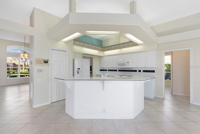 13783 Palmetto Point Ct, Port Charlotte, FL 33953 - kitchen featuring white appliances, light tile patterned flooring, white cabinetry, a chandelier, and a high ceiling
